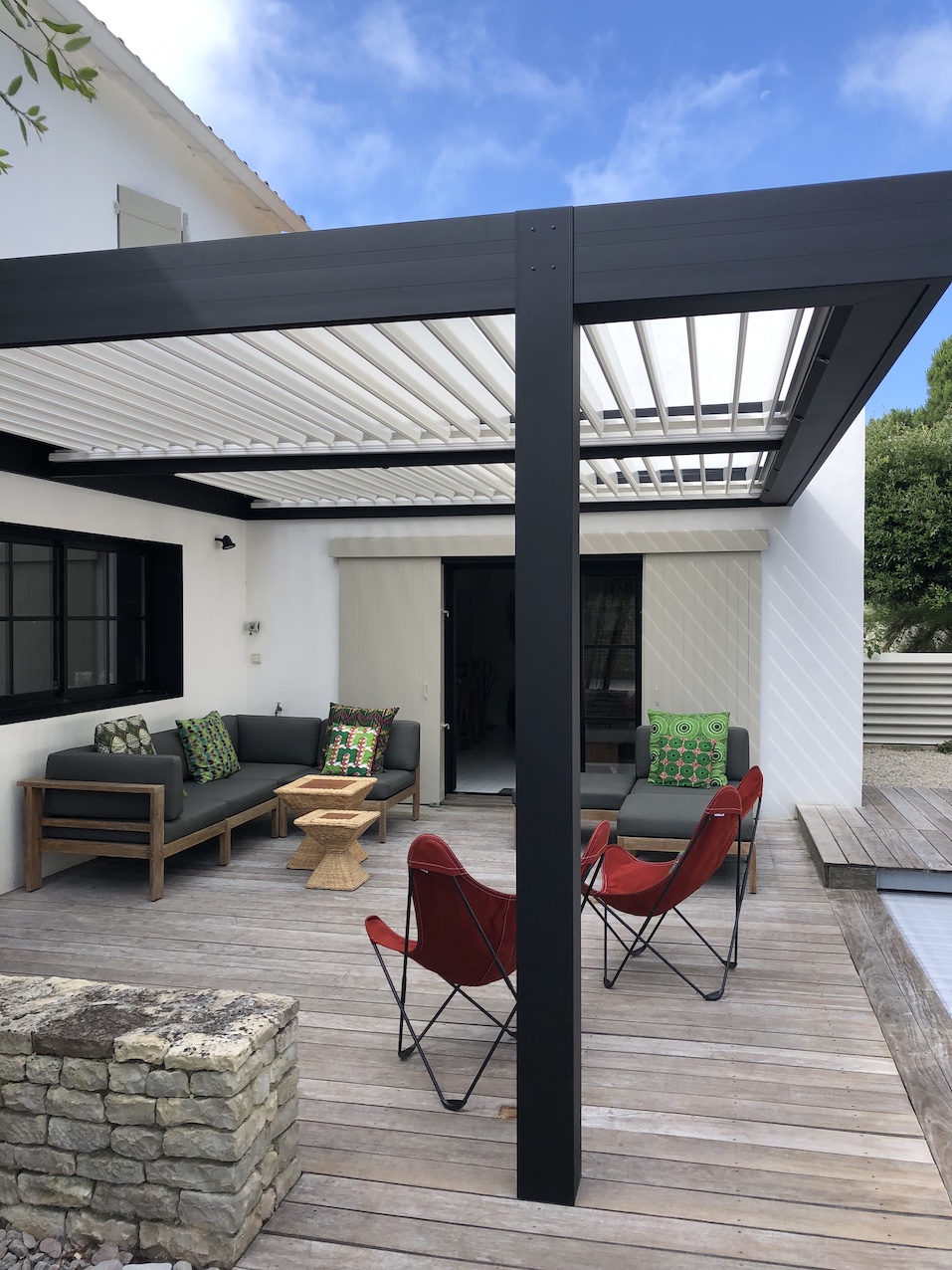 Lames orientables d’une pergola protégeant du soleil la terrasse et les baies vitrées de la maison